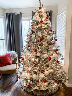 a decorated christmas tree in a living room with red and white ornaments on the top