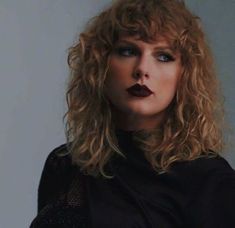 a close up of a person with long hair and lipstick on her lips, wearing black