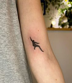 a person with a tattoo on their arm that has a silhouette of a man jumping