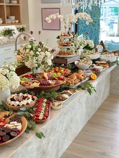 a table filled with lots of food on top of a wooden floor covered in white flowers