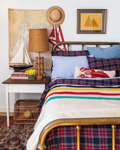 a bed room with a neatly made bed next to a lamp and pictures on the wall