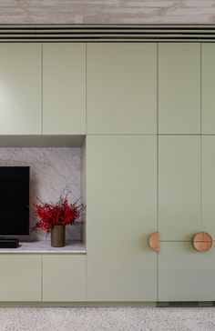 a tv sitting on top of a wooden cabinet next to a vase filled with flowers