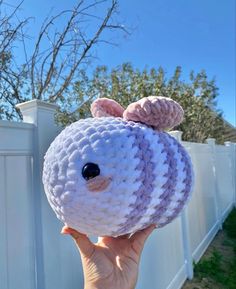 someone holding up a stuffed animal in front of a white fence