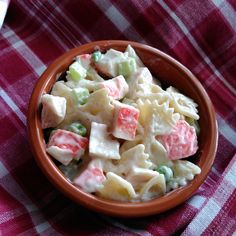 a bowl filled with pasta salad on top of a red and white checkered table cloth