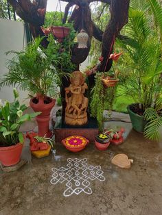 an outdoor area with potted plants and decorative items on the ground, including a buddha statue