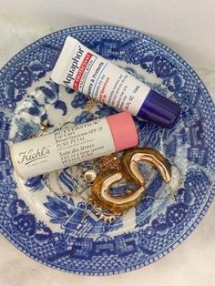 a blue and white plate topped with items like lipstick, toothpaste and scissors