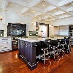 a large kitchen with an island in the middle and bar stools at the end