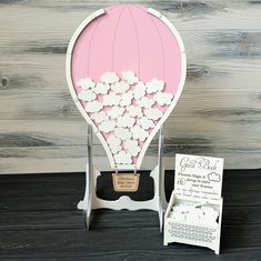 a pink and white hot air balloon with flowers on the front is next to a card holder