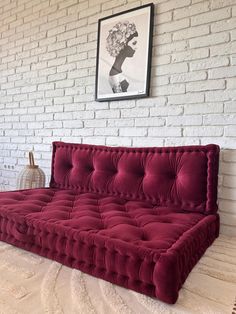 a red couch sitting in front of a white brick wall