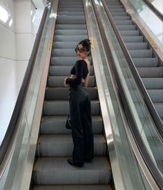 a woman standing on an escalator with her arms crossed