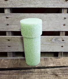 a green cup sitting on top of a wooden table next to a pallet wall