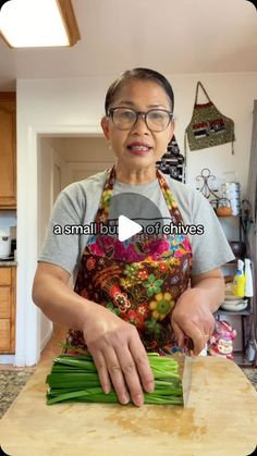 a woman in an apron chopping green beans on a cutting board with a knife