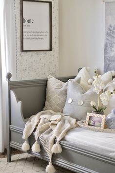 a gray daybed with white pillows and pictures on the wall above it, along with other decorative items