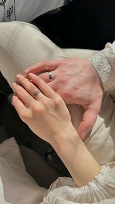 two people holding each other's hands while sitting on a couch with white pillows