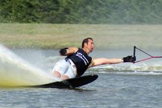 a man on water skis being pulled by a boat in the water with trees in the background