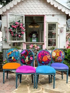 four colorful chairs sitting in front of a building