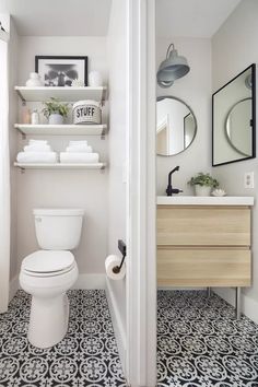 a white toilet sitting in a bathroom next to a wooden shelf filled with towels and other items