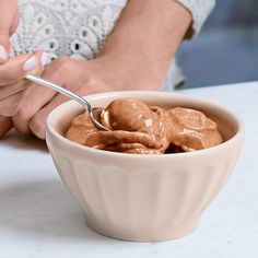 a woman is spooning into a bowl of ice cream