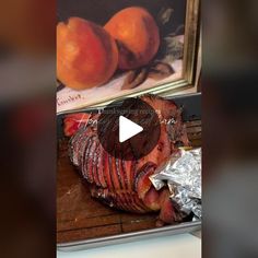 a piece of meat sitting on top of a counter next to some oranges and a painting