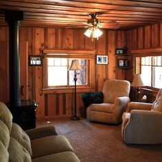 a living room with wood paneling and two recliners in front of a fireplace