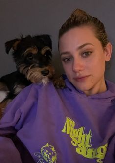 a woman sitting next to a small dog