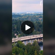 an aerial view of a highway and bridge in the distance with trees on both sides