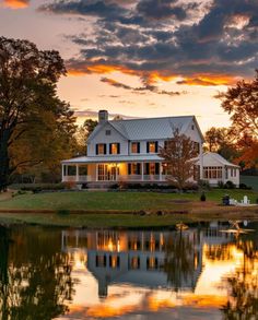 a large white house sitting on top of a lush green field next to a lake