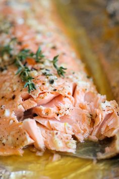 a piece of salmon on a foil pan with seasoning sprinkled on top