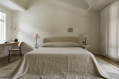 a bed sitting in a bedroom next to two lamps on either side of the bed