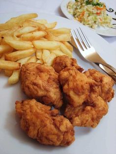 fried chicken, french fries and coleslaw on a white plate with silverware