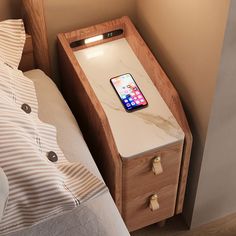 an iphone charging on a nightstand next to a bed