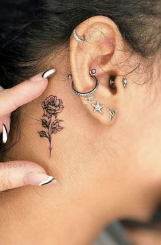 a woman's ear with some piercings on her neck and behind the ear