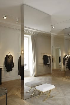 a room filled with lots of clothes on display in front of a window and two tables