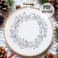 a cross stitch pattern with pine cones and berries on it, surrounded by evergreen needles