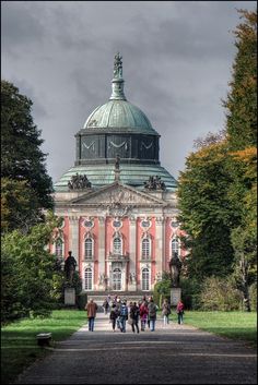 people are walking around in front of a large building with a clock on it's roof