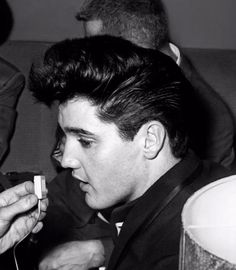 a black and white photo of a young man looking at his cell phone while sitting on a couch