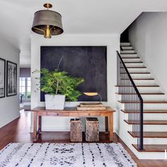 a living room with white walls and wooden floors, stairs leading up to the second floor