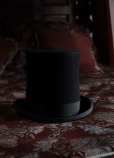 a black hat sitting on top of a bed