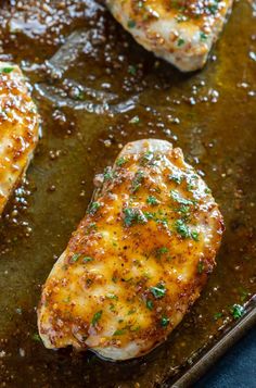 three pieces of chicken in a pan with sauce and parsley on the side, ready to be cooked