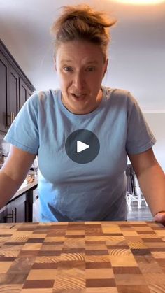 a woman standing in front of a wooden cutting board