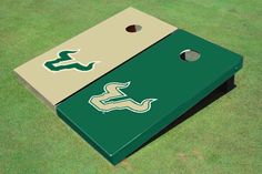 two green and beige cornhole game boards sitting on top of a grass covered field