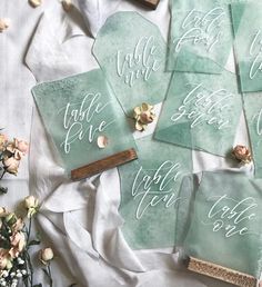 six tags with calligraphy on them sitting next to some dried flowers and other items