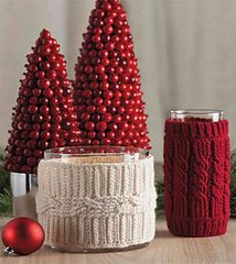 three knitted christmas trees sitting on top of a table next to a red ornament