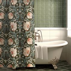 a bath tub sitting next to a shower curtain with flowers on it in a bathroom