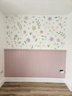 an empty room with painted flowers on the wall and wood flooring in front of it