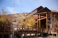 a large wooden house sitting on the side of a hill next to trees and rocks