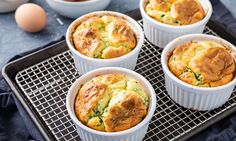 four small white dishes filled with food on top of a cooling rack next to eggs