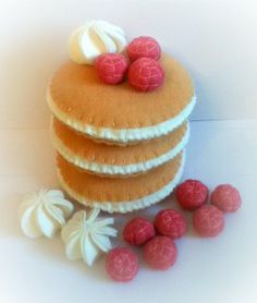 a stack of pancakes with raspberries on top and white icing next to it