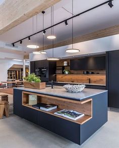 an open concept kitchen and dining area with wooden ceiling beams, black cabinets and counter tops