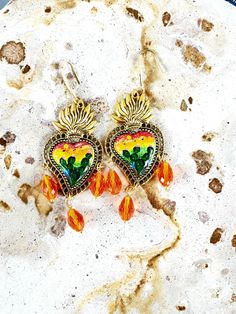 Detailed and beautiful artistically painted earrings, they are detailed painted taking a miniature painting of a cactus with a sunset with reddish sky and adorned with glass beads, and are protected with several layers of jewelry varnish, improving the quality and durability of the earrings. These earrings are inspired by our Mexican culture and hand painted; They are the ideal gift because they combine with any outfit both day and night, enhancing the beauty of whoever gets them and attracting attention for being unique hand-painted pieces, the Ideal gift for Mother's Day and holidays. Features/ Product info Note: The earrings in stock have some differences because they are hand painted. The Main Material: Zinc Alloy (Gold) Color: Multicolor - Earrings: 3.6 in (H) 1.75 (W) -Earrings weigh Bohemian Earrings With Artistic Design For Gift, Artisan Heart Earrings As Gift, Artisan Heart Earrings For Pierced Ears As Gift, Bohemian Teardrop Jewelry With Artistic Design, Artistic Heart Earrings As Gift, Artsy Orange Jewelry With Matching Earrings, Artistic Heart-shaped Earrings For Gift, Artisan Earrings With Artistic Design For Festivals, Hand Painted Earrings For Festivals